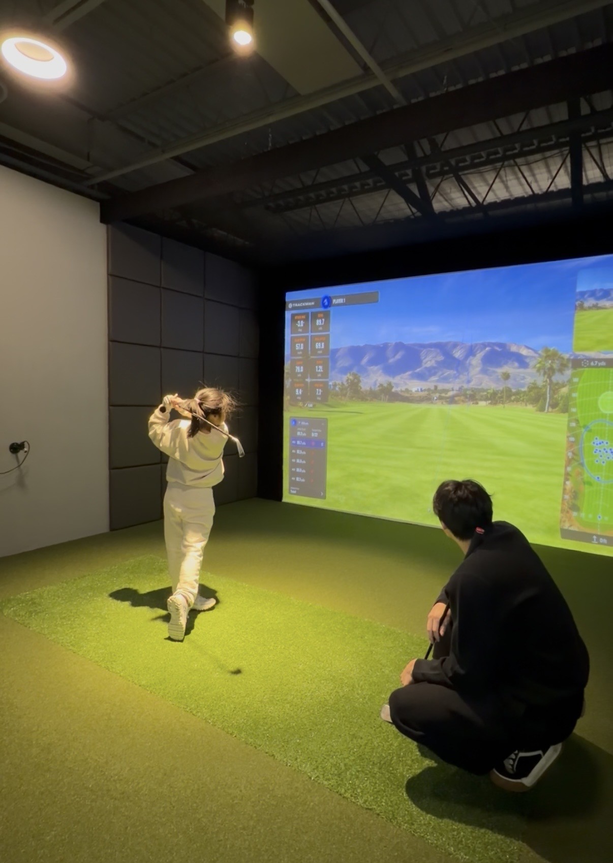 A junior golfer training with a Vanguard coach on TrackMan